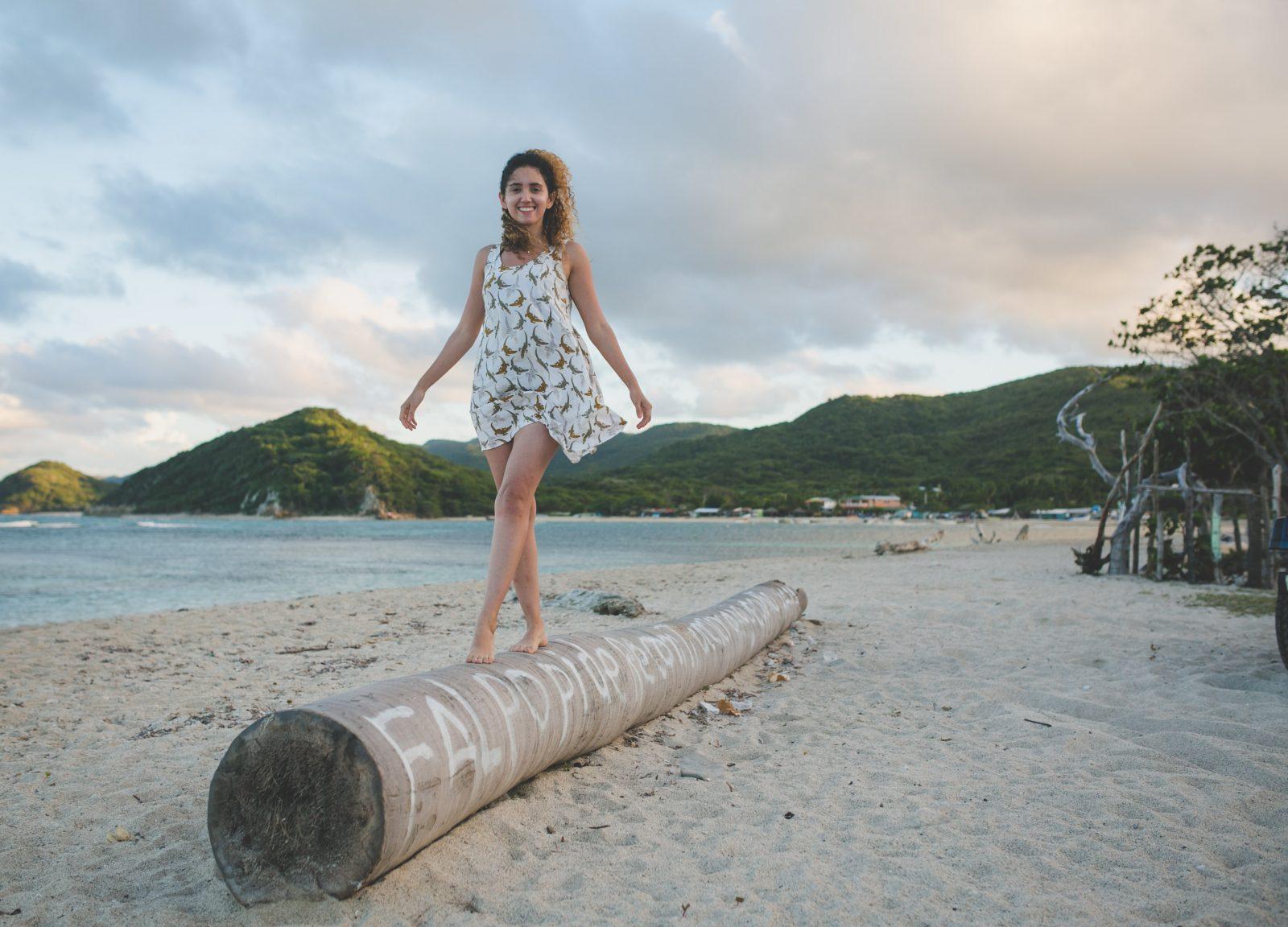 A woman standing on a tree log on the beach at Buen Hombre.