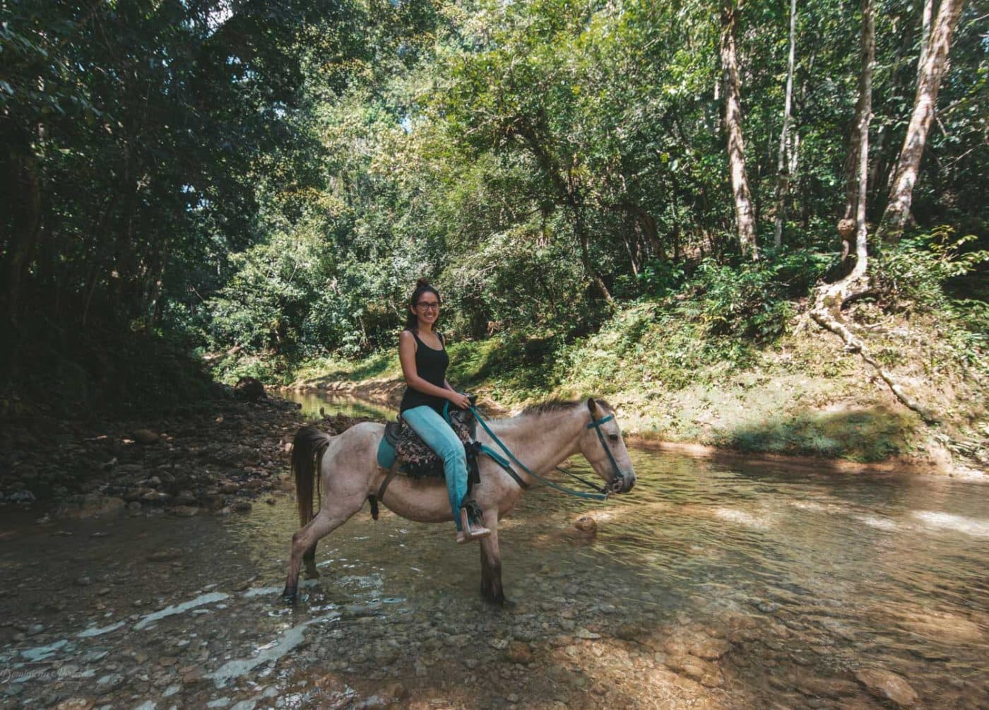 A woman horse back riding to a waterfall in the Dominican Republic.