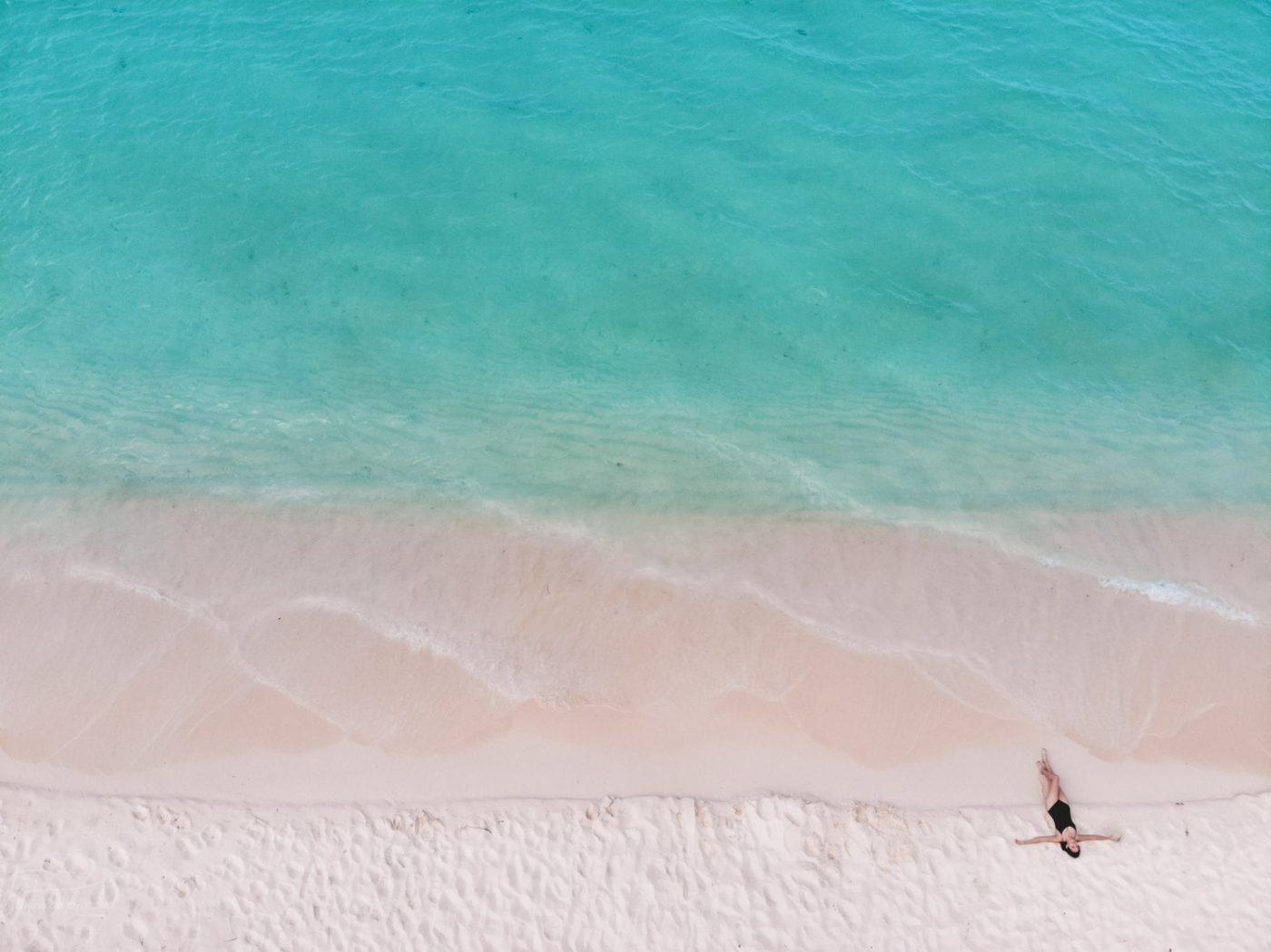 A person lying down on the pristine sand by the turquoise blue water of Bahia de las Aguilas, one of the best places to visit in the Dominican Republic.