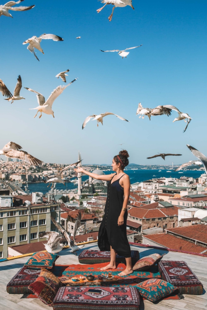 A woman playing with birds at secret rooftops in Istanbul, Turkey.