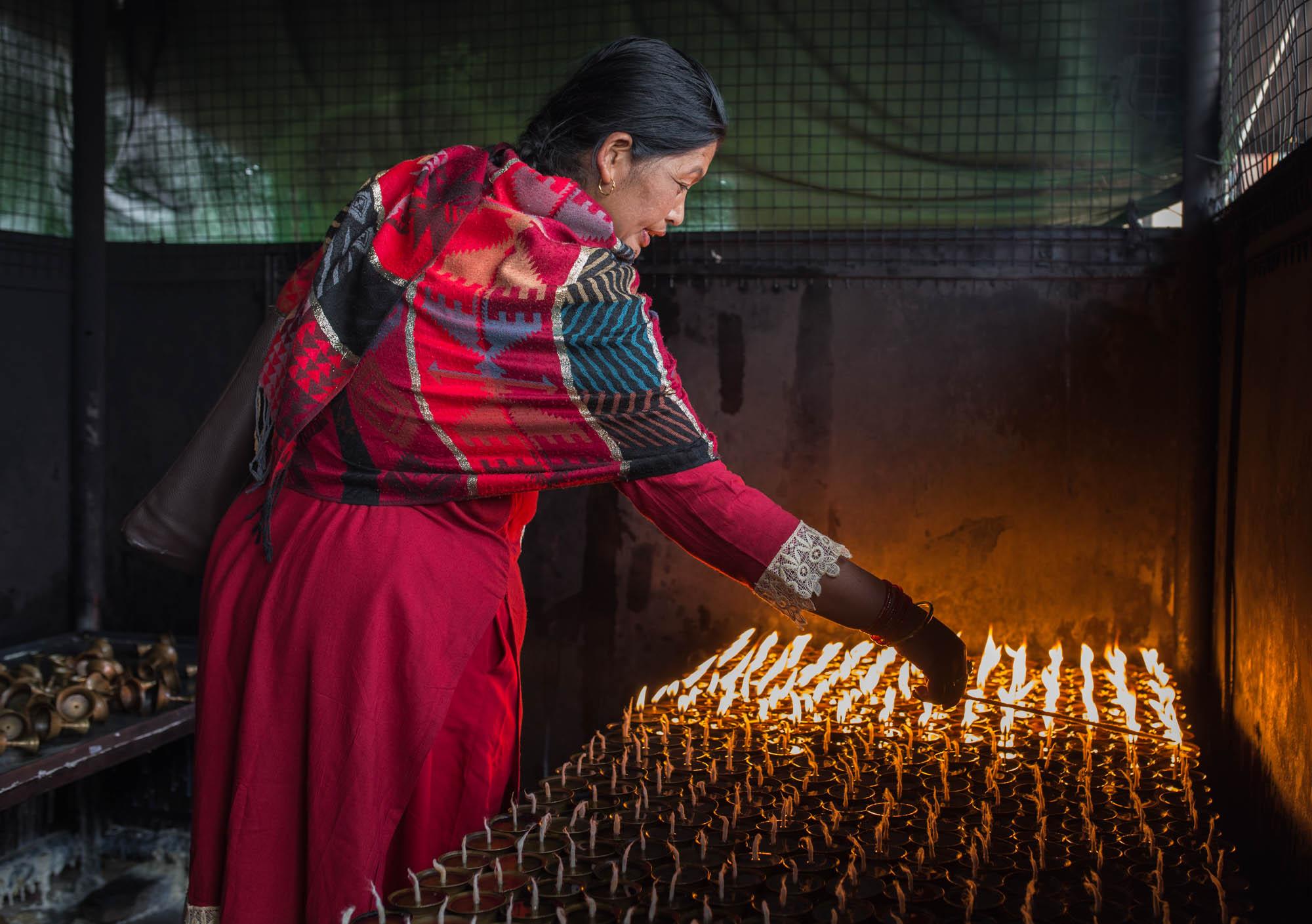 A woman lighting candles in Boudhanath Stupa, Kathmandu,