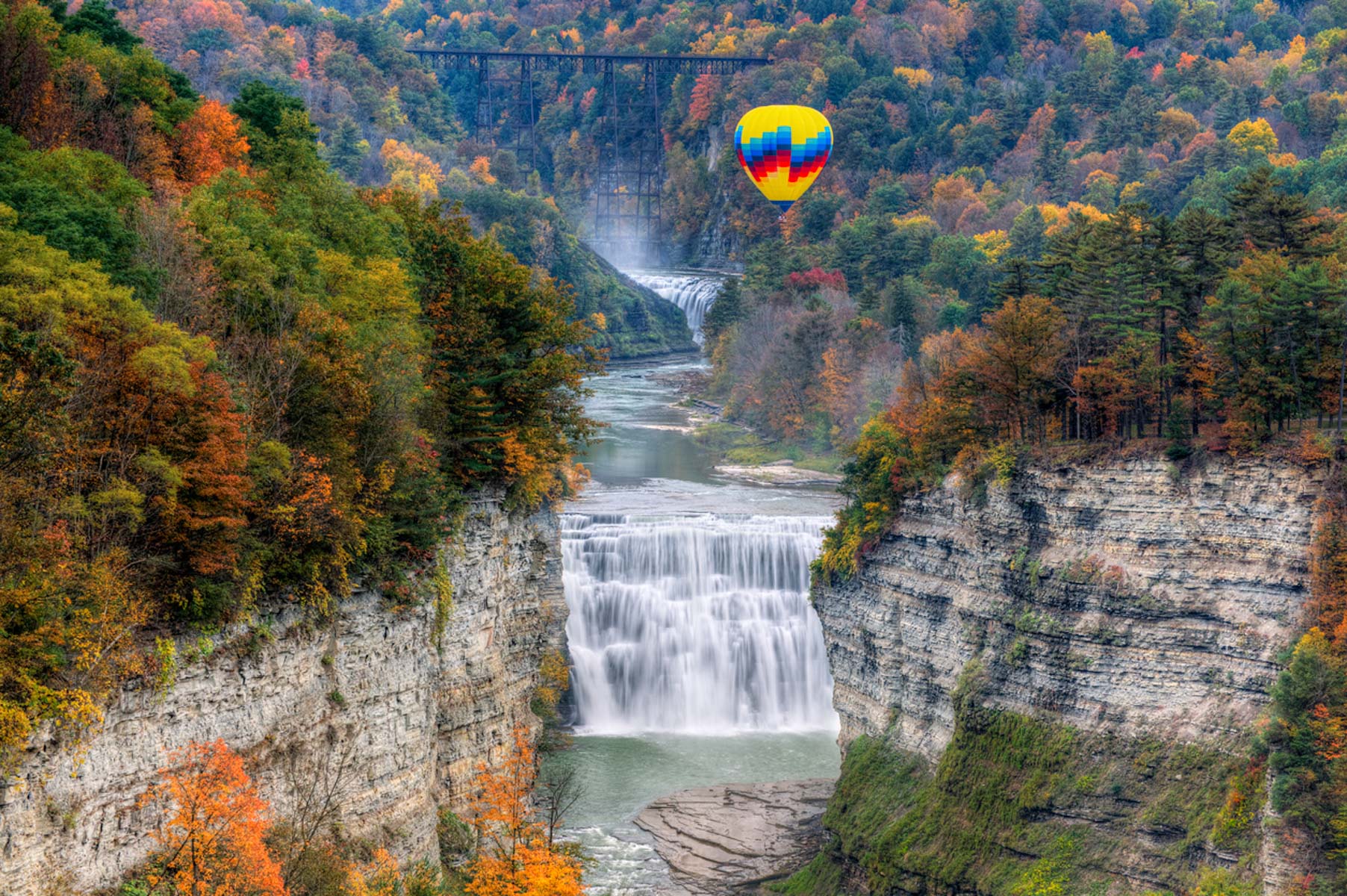 a waterfall with a hot balloon floating over it