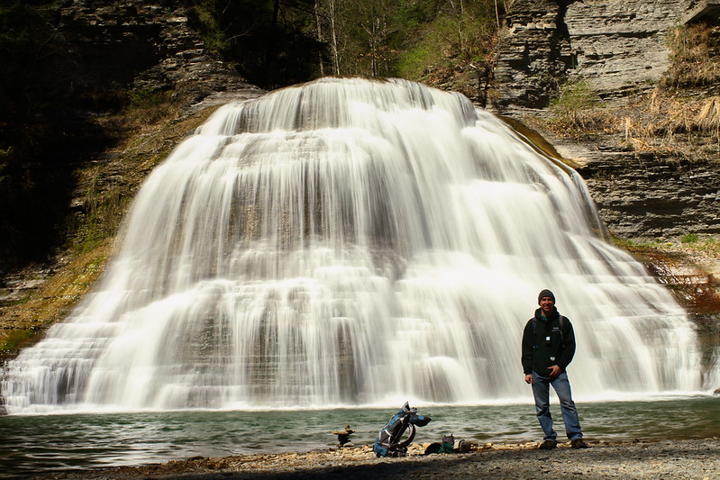 a guy standing by a waterfall in the finger lakes