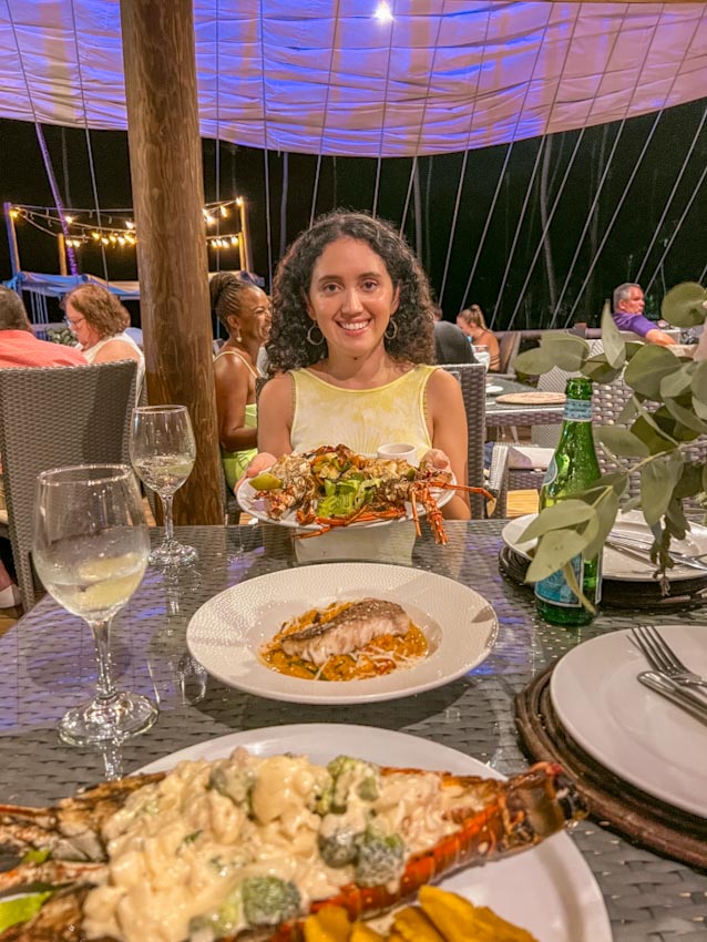 A woman at a restaurant in the Dominican Republic with table of plates of food and glasses of drinks.