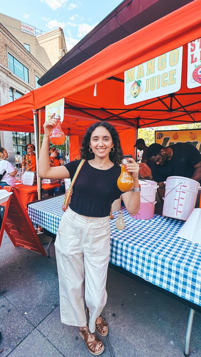 A woman holding drinks at Bronx Night Market
