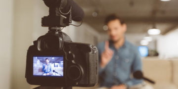 Männlicher Vlogger, der Inhalt für seinen Videoblog aufzeichnet. Junger Mann im Fokus auf Digitalkamerabildschirm.