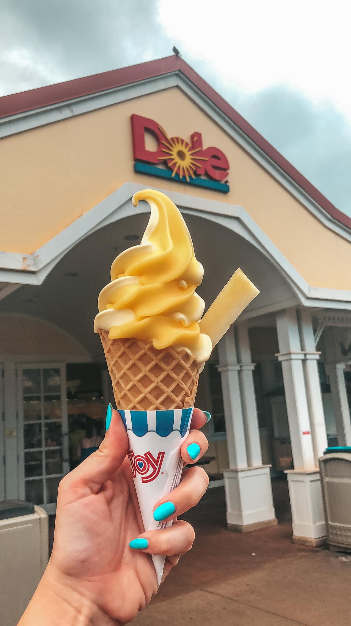 Dole whip cone being held up in front of Dole Plantation on Oahu's North Shore