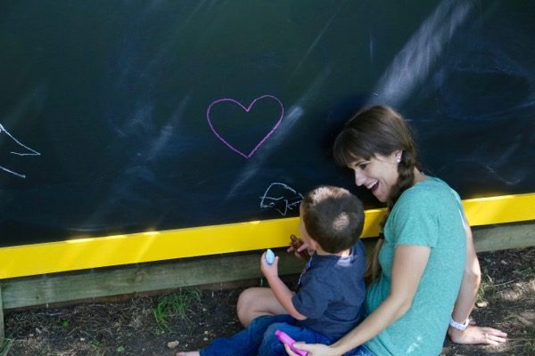 Toddler and mom drawing on outdoor chalkboard