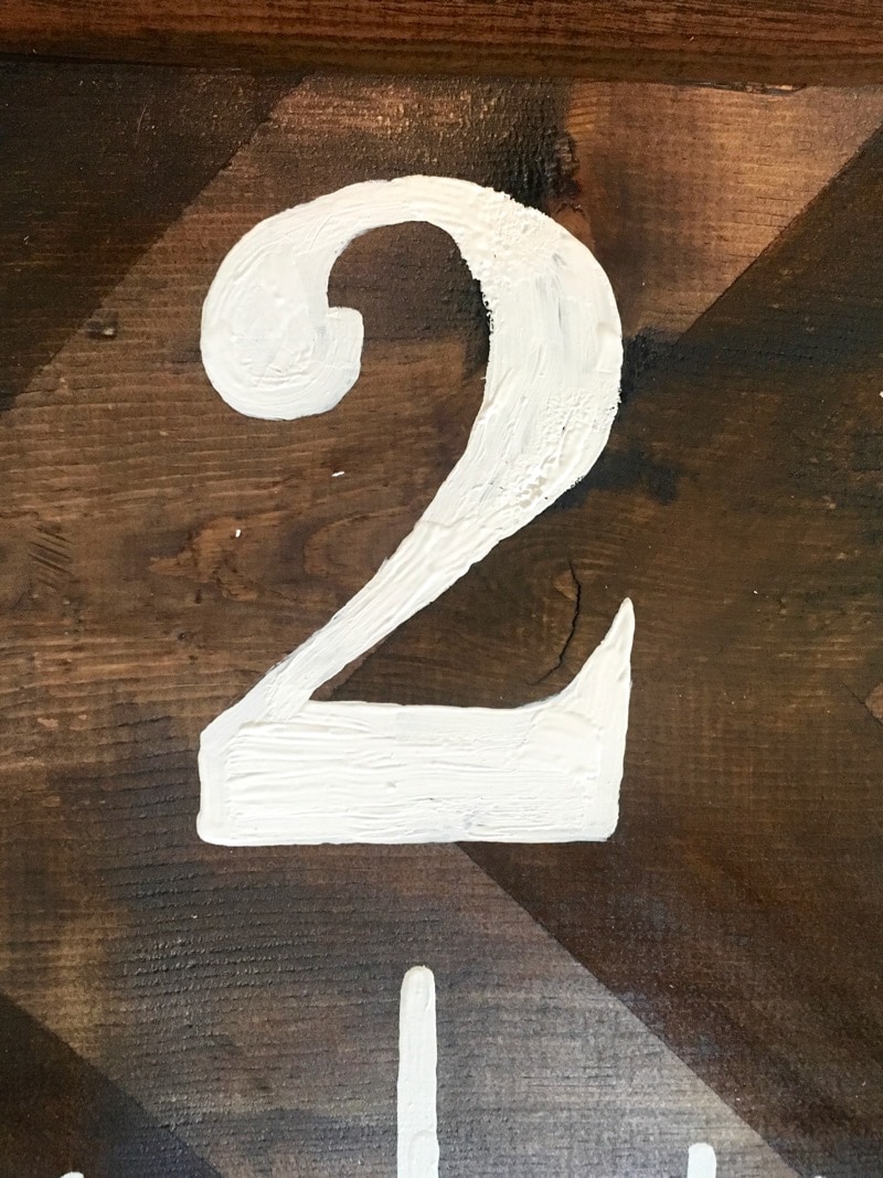 the number 2 painted on a wooden growth chart