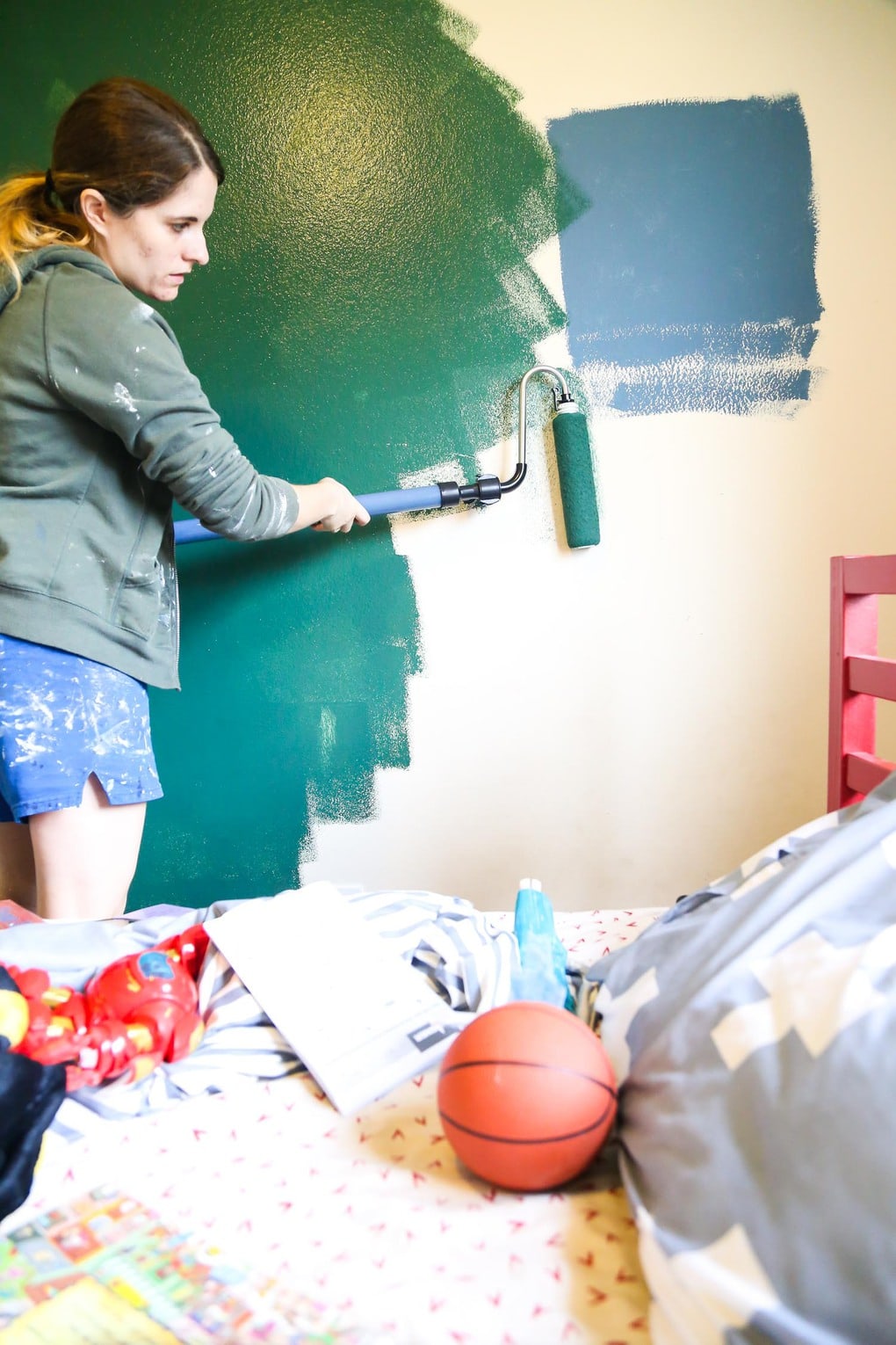 Woman painting a green accent wall using a Wagner Smart Roller