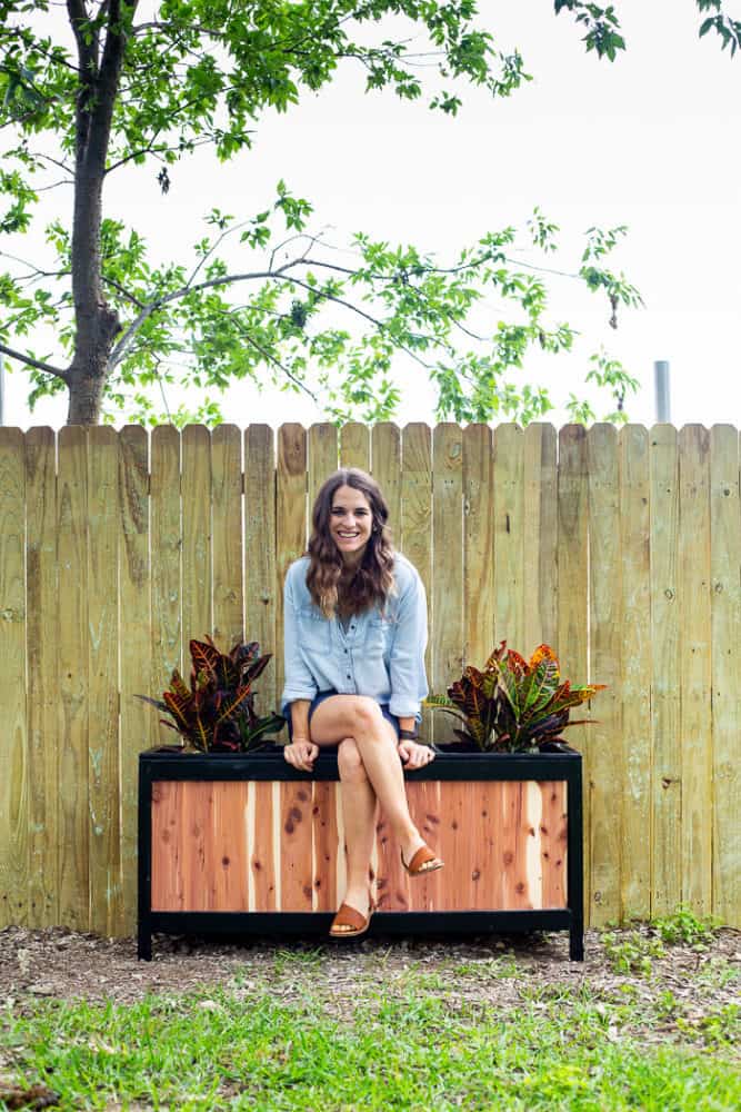 Woman sitting on a DIY cedar planter 