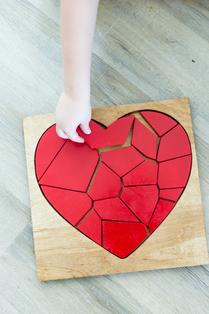 A boy's hand putting a piece into a DIY wood puzzle