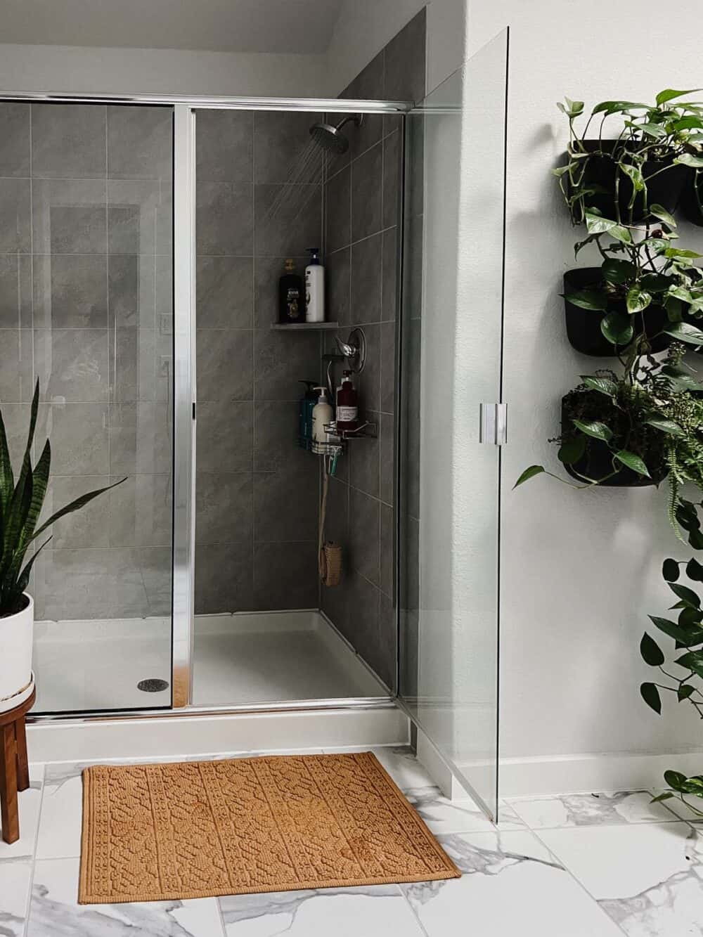 A running shower in a bathroom filled with plants 