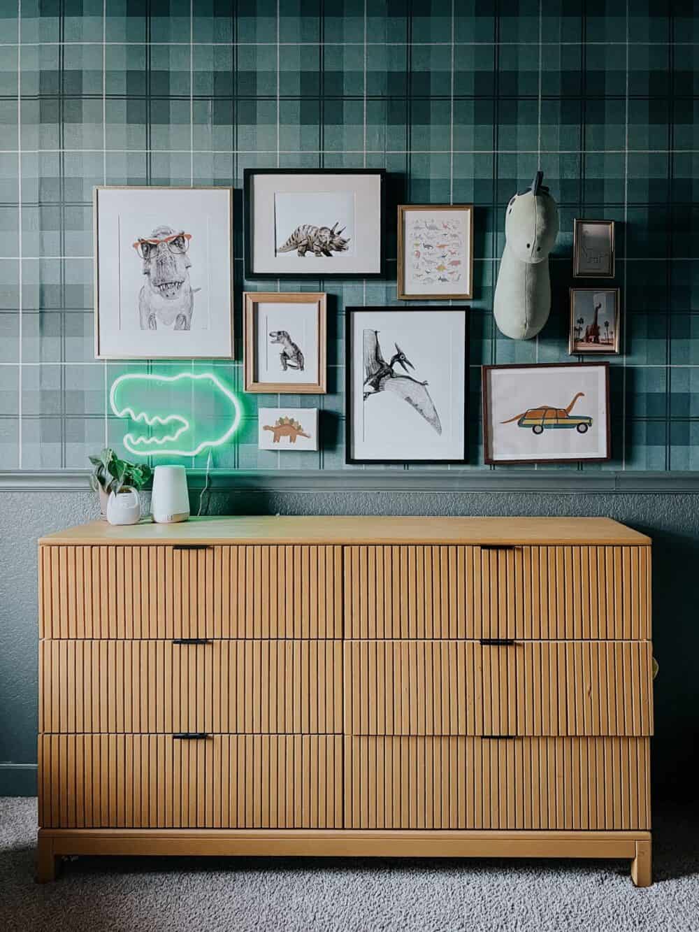 Dinosaur themed gallery wall with a yellow dresser underneath