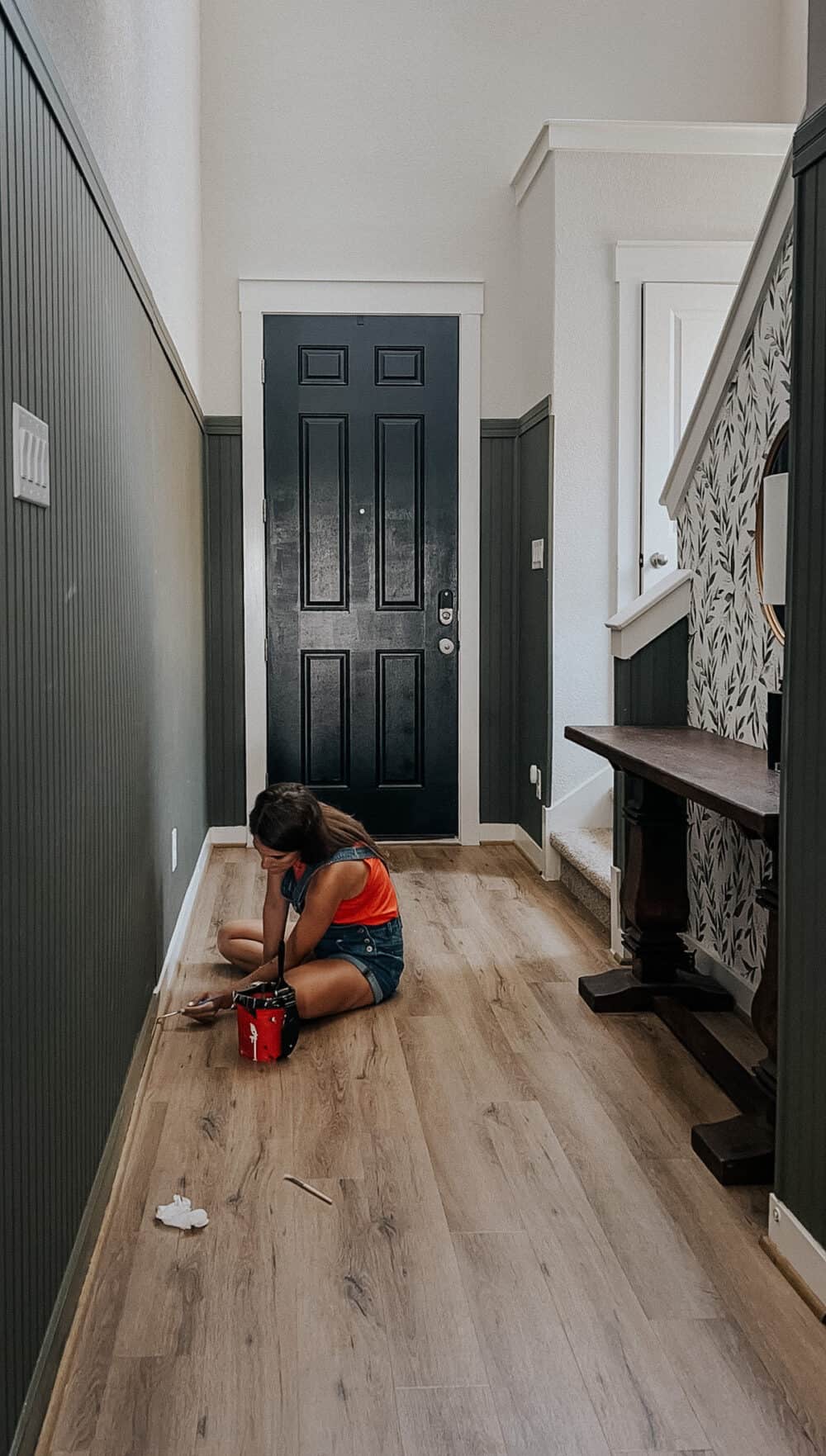 Woman painting baseboards in entry