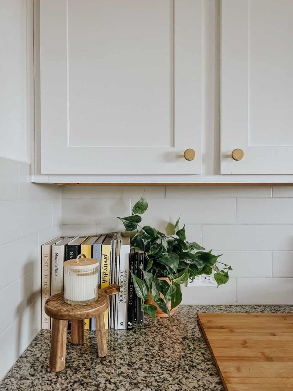 Small wood pedestal with a candle on top of it sitting on a kitchen counter 