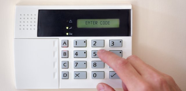 A hand entering a code on a security alarm system.