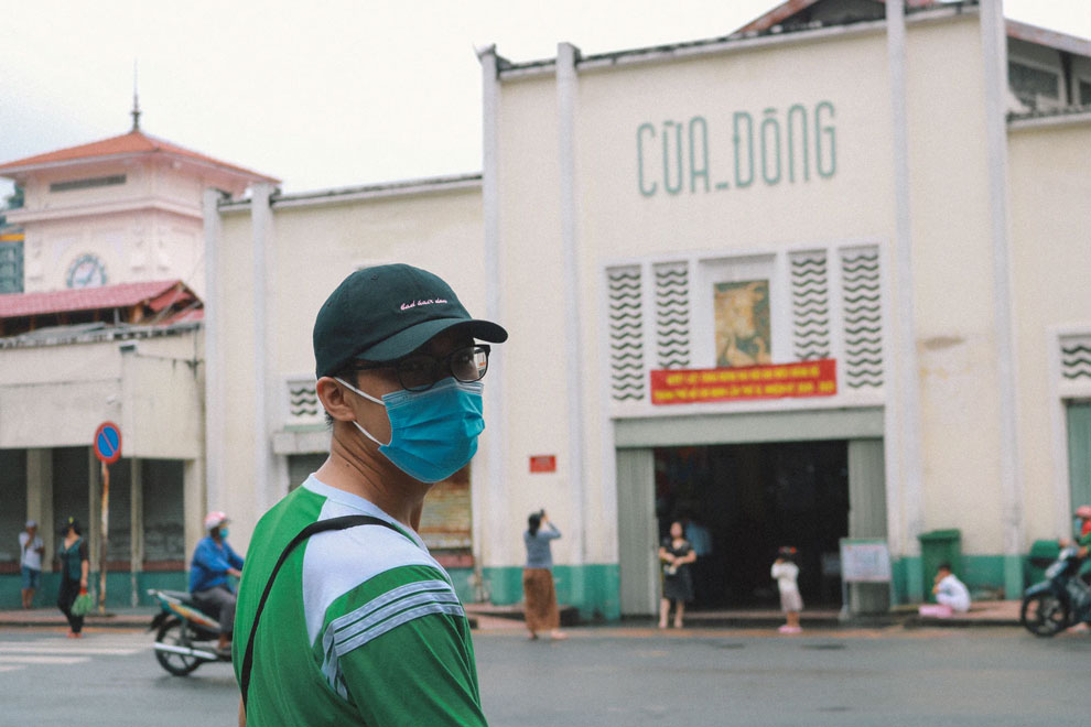 Vietnamita con mascara en la entrada de un mercado 