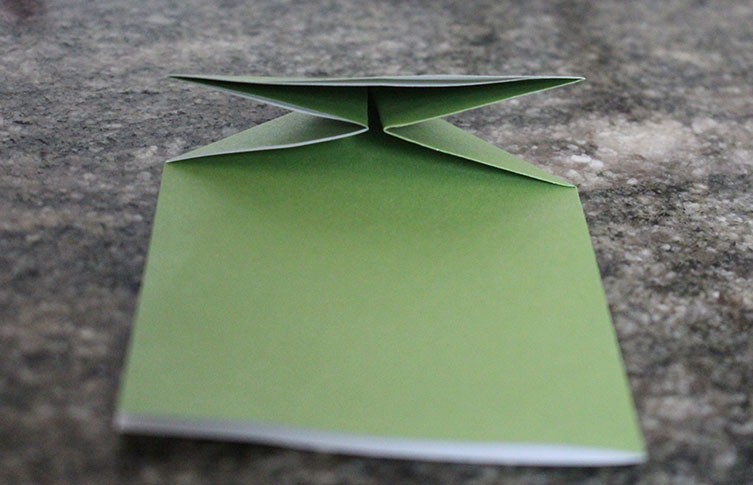 Push the sides of the paper together and press it down to create a triangle shape