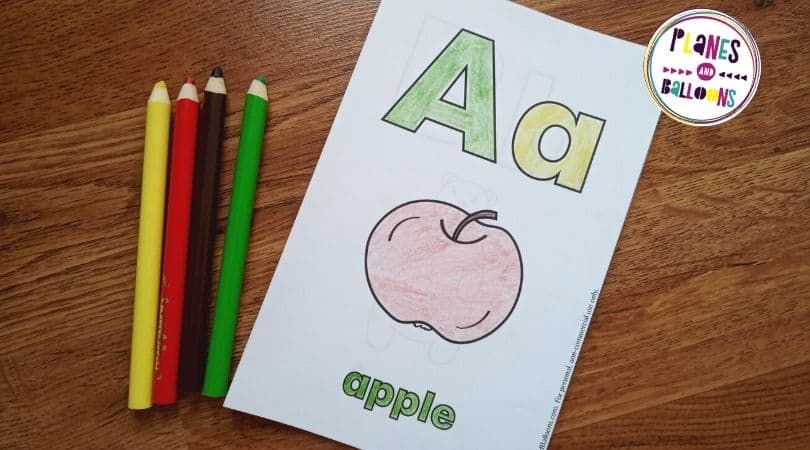 ABC coloring booklet on wooden background with some colored pencils