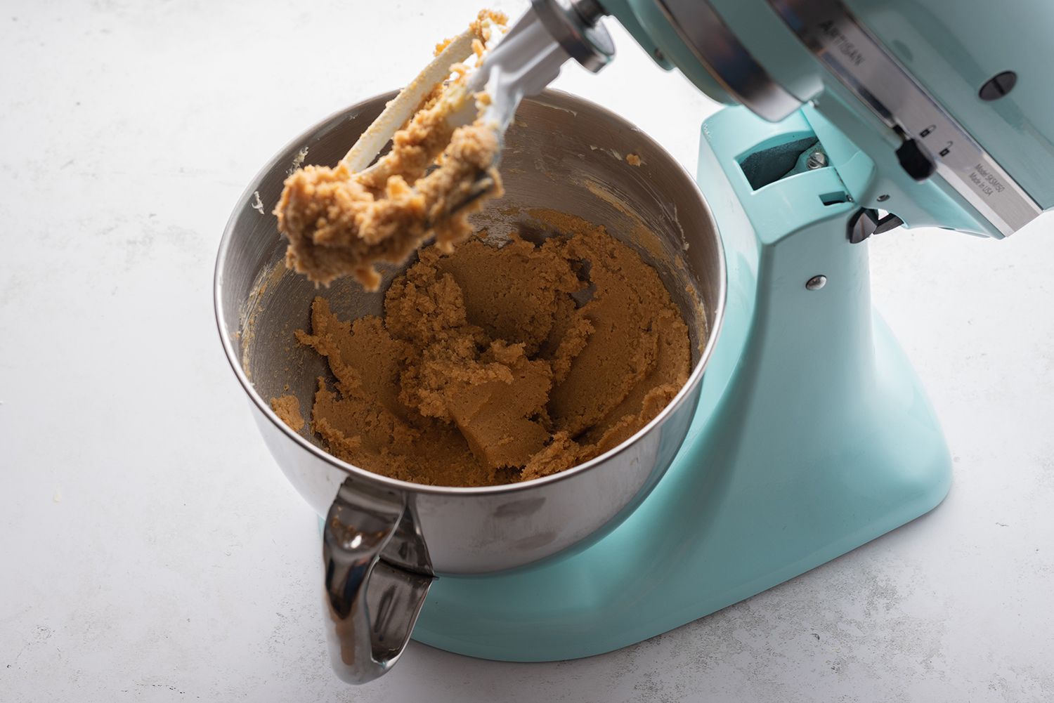 Sugar and creamed butter in a blue stand mixer 