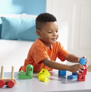 boy playing with melissa and doug wooden stacking train