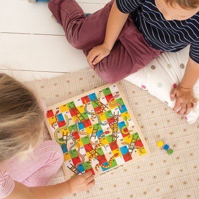 young players with traditional snakes and ladders family board game