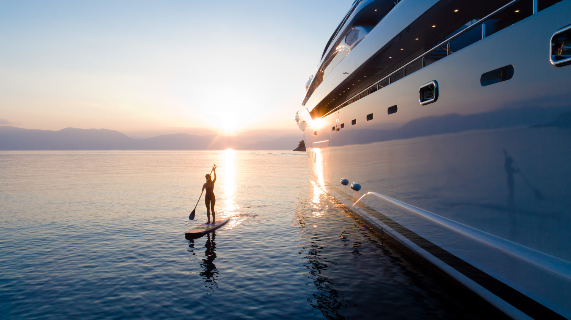 Yacht and woman on paddle board