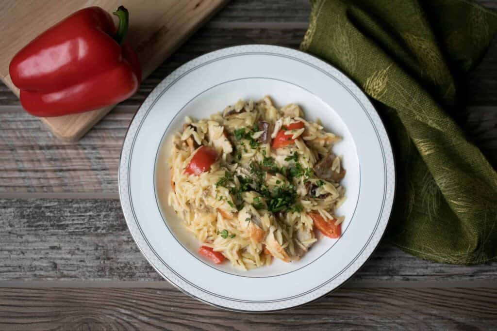 bowl of creamy orzo pasta with chicken and red peppers
