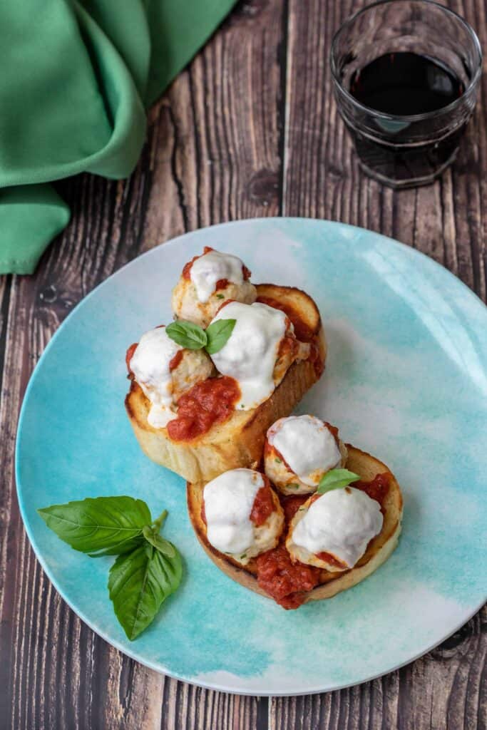 Chicken parmesan meatballs on blue plate with red wine and green napkin