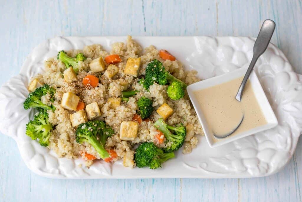 quinoa grain bowl with broccoli, carrots, tofu, and sesame-ginger dressing
