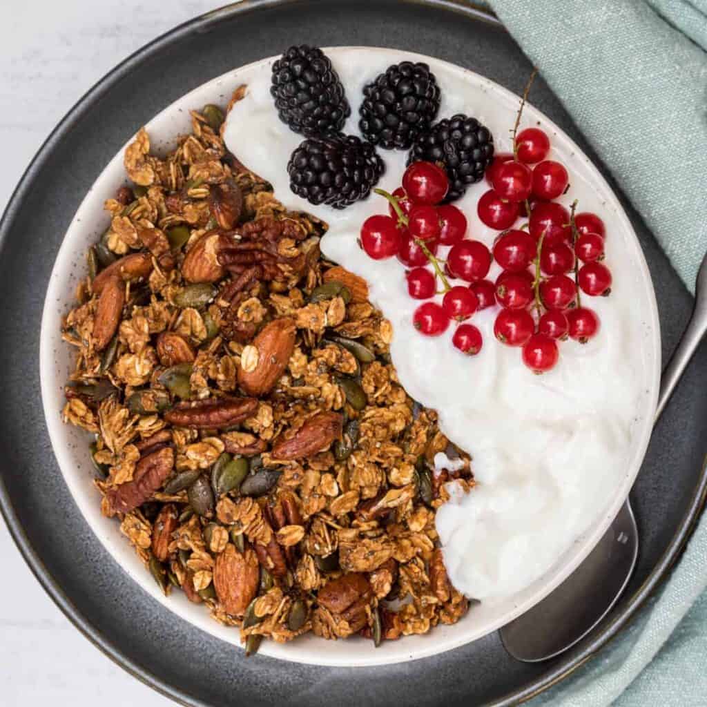 pumpkin seed granola on yogurt in bowl with berries
