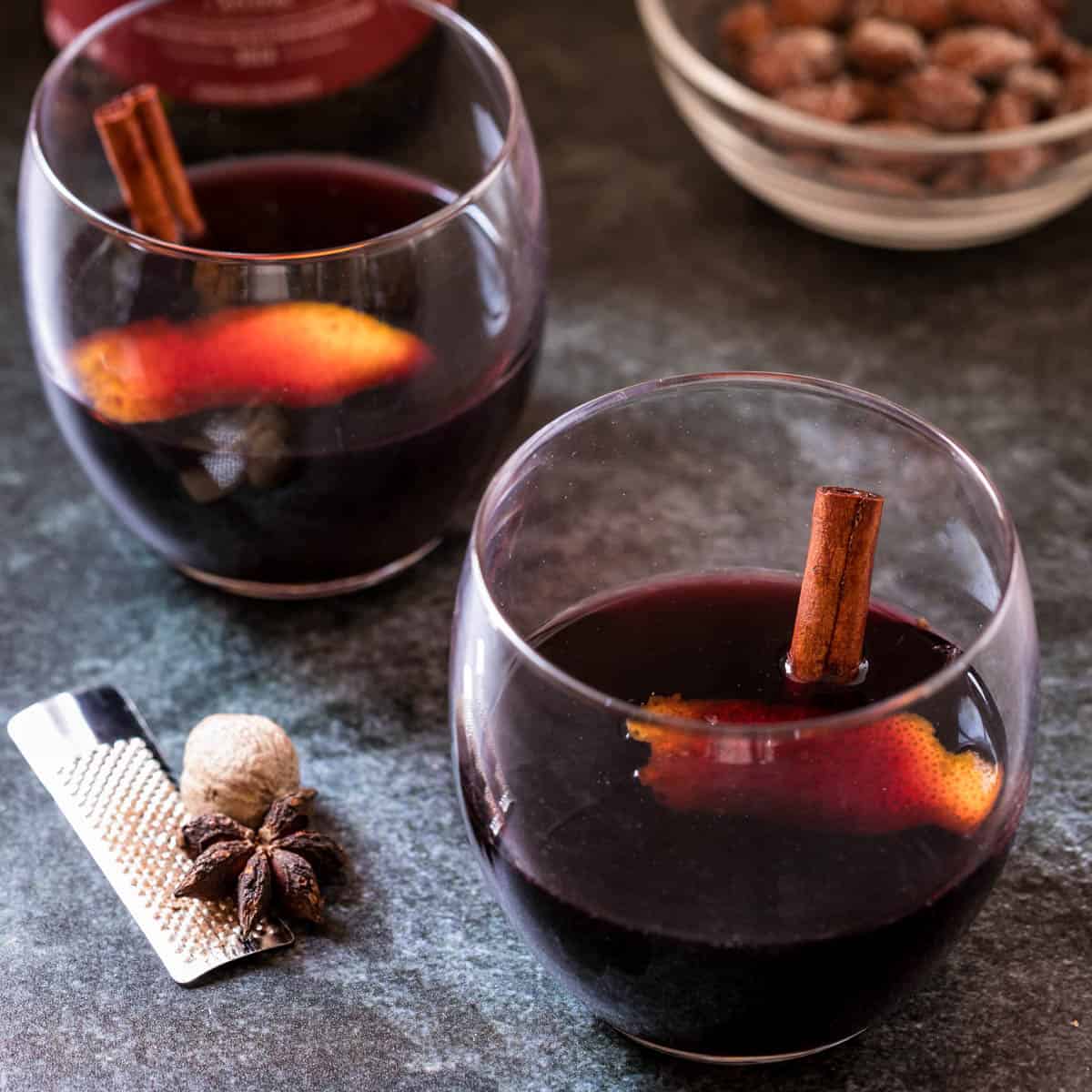 two glasses Vin Chaud with nuts in background and nutmeg and star anise