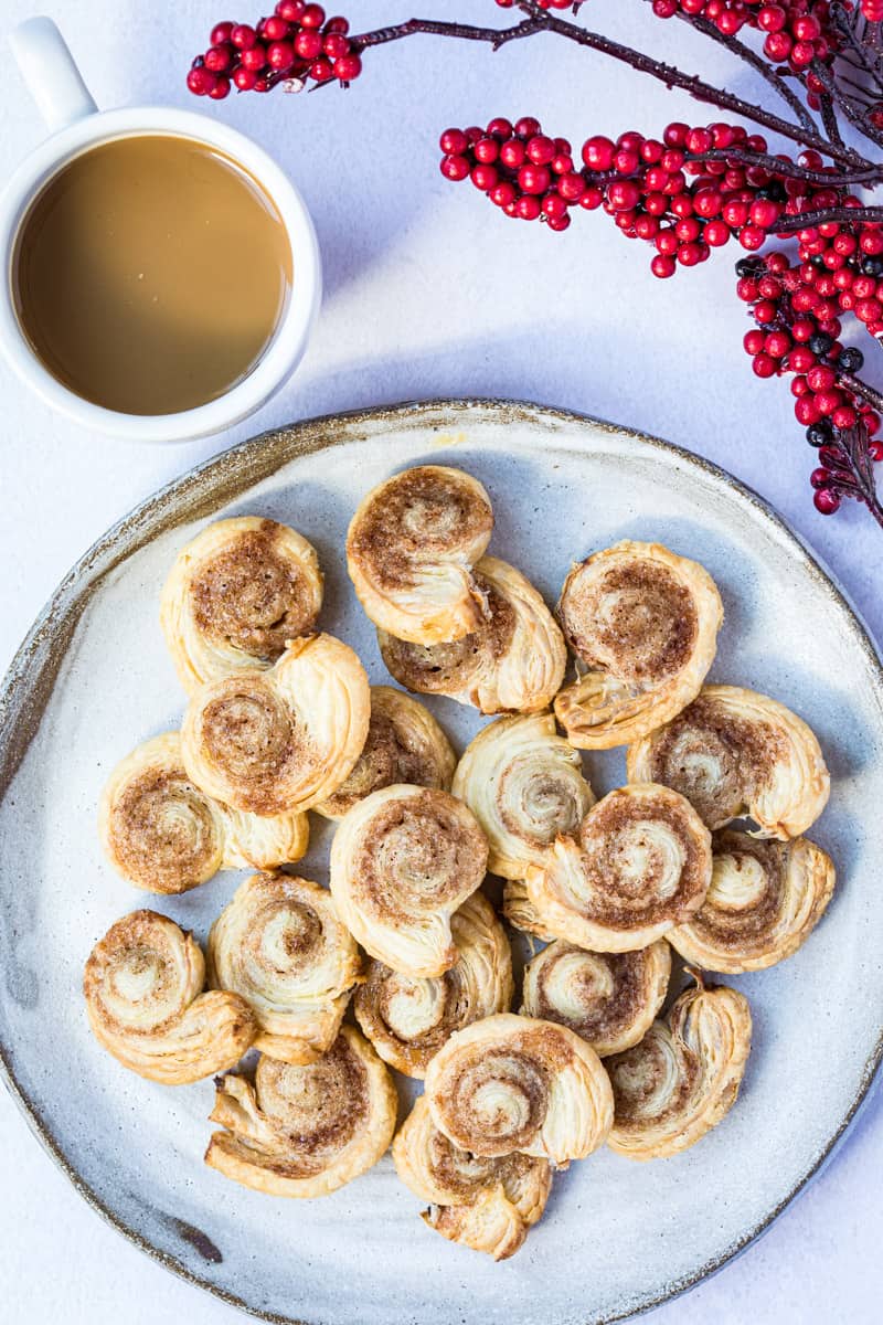 plate with cinnamon rolls next to mug with coffee and red berries