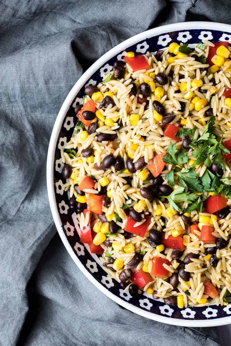 big bowl of orzo pasta salad with black beans and corn next to napkin