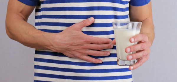Man with hand on stomach holding glass of milk