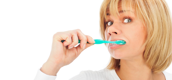 Mature woman brushing her teeth with puzzled expression