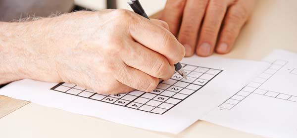 Senior playing sudoku a great way to keep the brain active and stave off cognitive diseases such as dementia