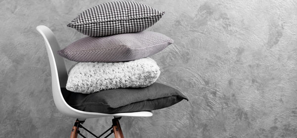 Stack of grey cushions on chair against grey backrgound