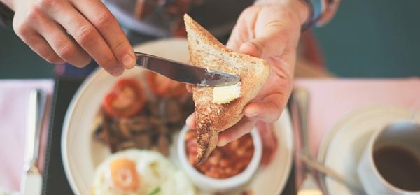 Woman's hands buttering toast over breakfast plate